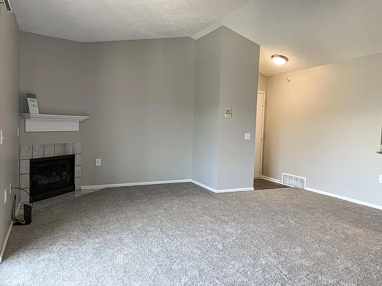 The Classic 1-bedroom floor plan features a spacious living room with plush carpet, soft-toned walls, and a cozy fireplace centerpiece.