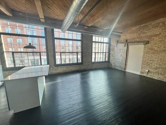 Spacious living room, open to the kitchen. The large original windows offer amazing light and views of the highly desired Third Ward!
