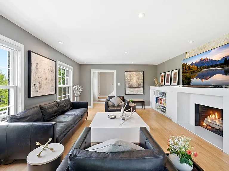 Main living room with tons of windows, built in shelving, and cozy fireplace.