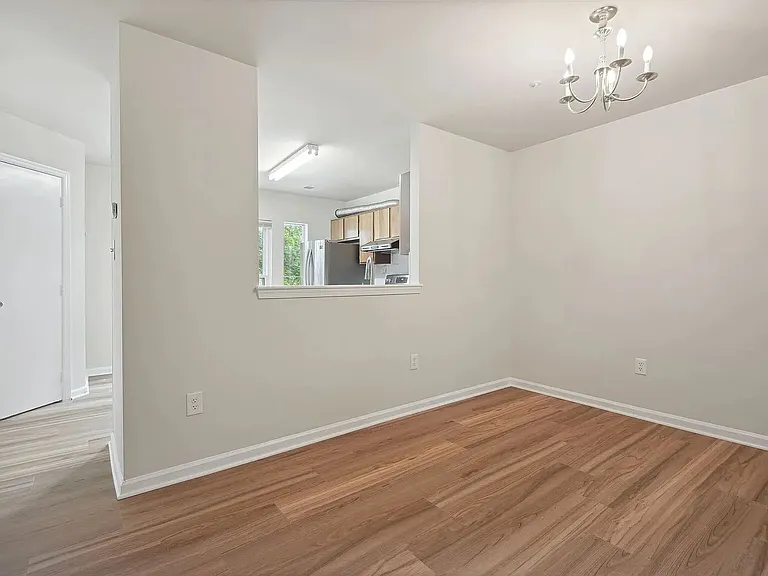 Overview of the dining area. The kitchen is visible beyond through the pass-through opening, while the half-bath door is visible on the left.