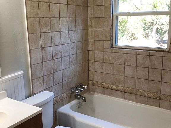 Full bathroom with tiled floors, tiled shower walls and large mirror with new light fixtures. Overlooking private back yard .