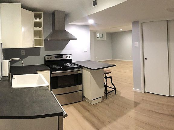 Kitchen with full range electric oven, dishwasher, garbage disposal, full-sized fridge, microwave, farm sink, bar seating, and ample storage.