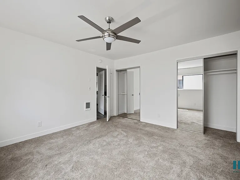 Bedroom with Two-Mirrored Closets, Ceiling Fan, and Carpet