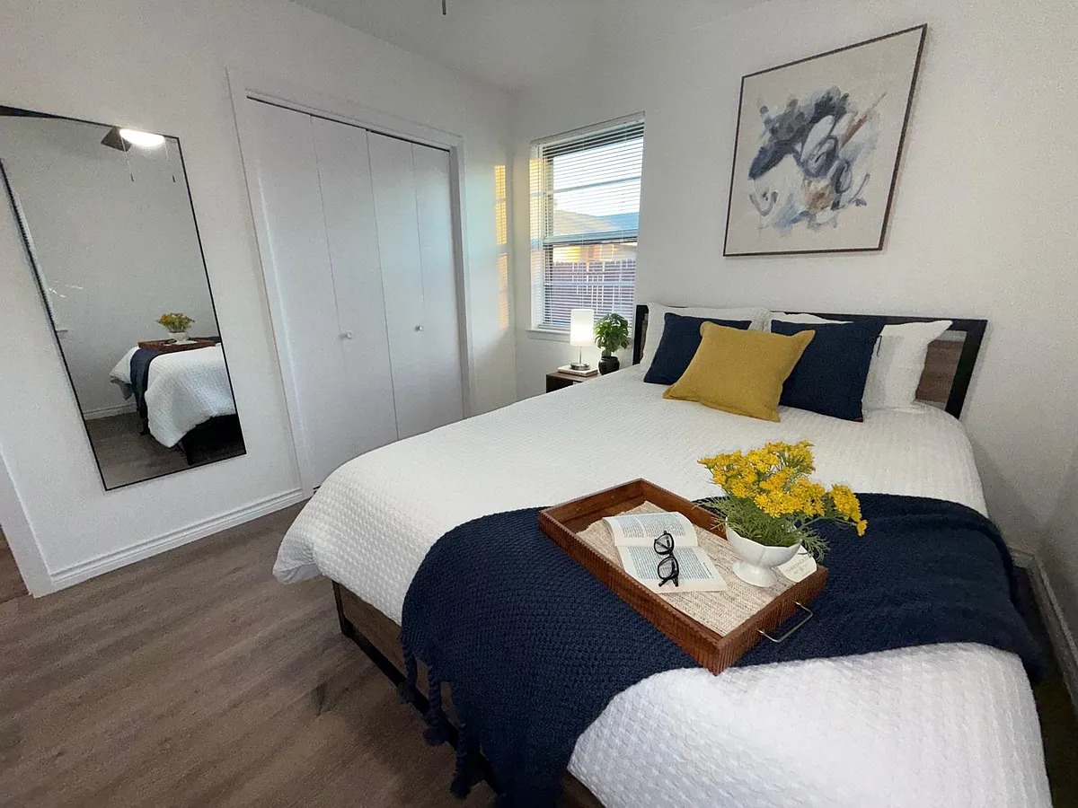 Well-appointed bedroom with a spacious bed, large mirrored closet, and a window for natural light. - Wisteria Way