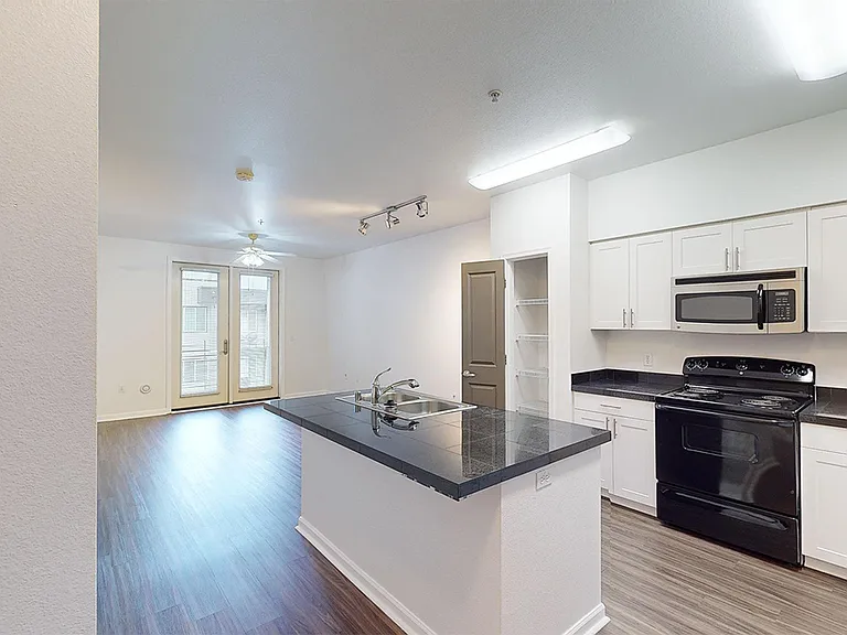 Apartment kitchen, dining and living room with wood-style flooring.