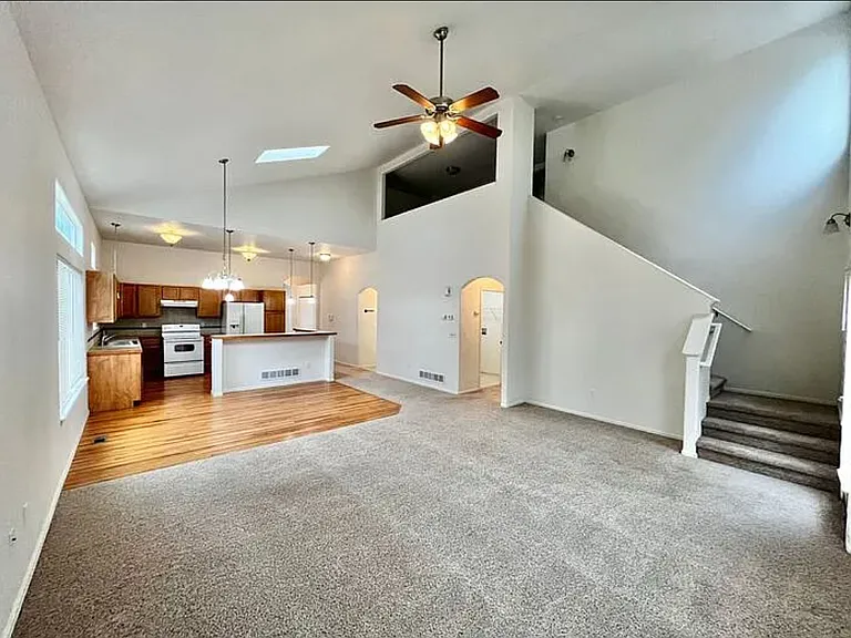 From living room, viewing dining area, bar, and kitchen on the left, archway to powder room and garage (right of bar), archway to laundry room and master bedroom (center), stairs leading to upper level, and loft (top-center).