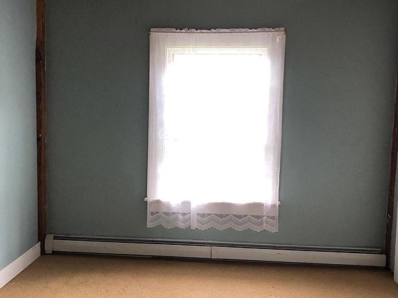 small bedroom with one closet and large window overlooking backyard meadow
