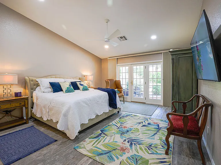 Master suite bedroom with king size adjustable split NECTAR hybrid copper cooling mattress, side tables with outlets, side seating, 60" TV, amoire, dedicated bath, walkin closet, with french doors to back patio