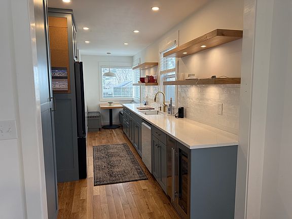 Kitchen with breakfast nook, open shelves, new appliances, and hardwood floors.