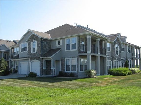 End unit with large covered balcony overlooking green space.