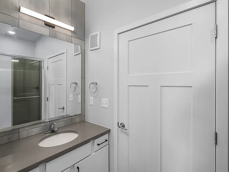 Sleek modern bathroom with minimalist design, featuring a spacious countertop, stylish mirror, and elegant fixtures. Sleek modern bathroom with minimalist design, featuring a spacious countertop, stylish mirror, and elegant fixtures.