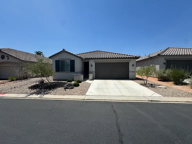 Front exterior with attached two-car garage and low-maintenance desert landscaping.