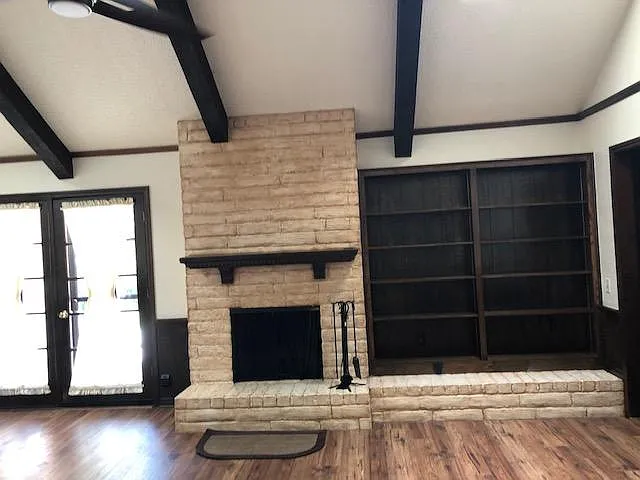 Fireplace with bookshelves and double doors leading to patio in backyard