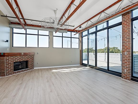 Main Living Room with Gas Fireplace, Industrial Fan, and Window Blinds