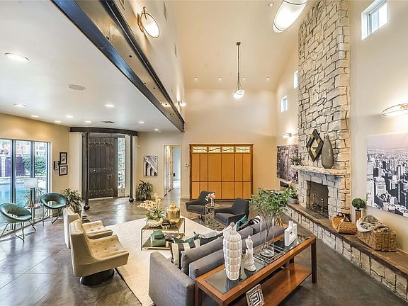 The impressive living room features two ceiling heights, steal beam, floor to ceiling limestone fireplace and hearth and a custom medieval-inspired front door.