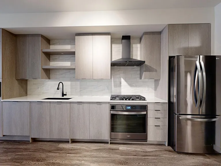 Apartment kitchen with black stainless steel appliances, quartz countertops, wood-style flooring, and custom Italian cabinetry.