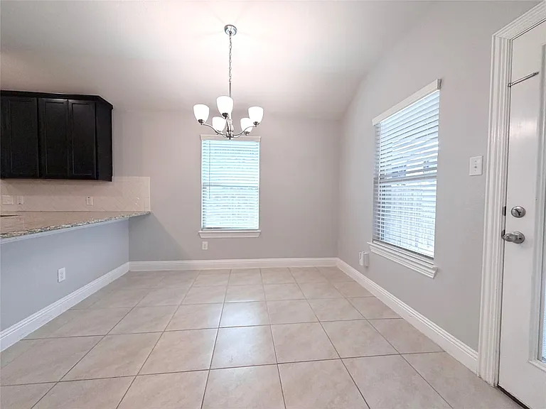 This spacious and inviting dining area is perfectly situated adjacent to the kitchen, creating an ideal layout for both daily meals and seamless entertaining. The room features elegant, easy-to-maintain neutral ceramic tile flooring throughout, accented b