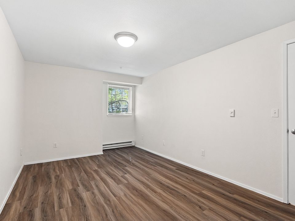 Spacious bedroom with wood-style flooring, neutral finishes, and natural light.