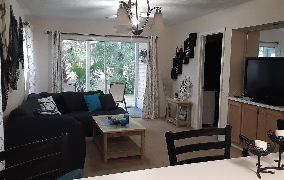 View of Living Room, Porch, and Backyard from Kitchen breakfast bar, with large screen TV on the right.