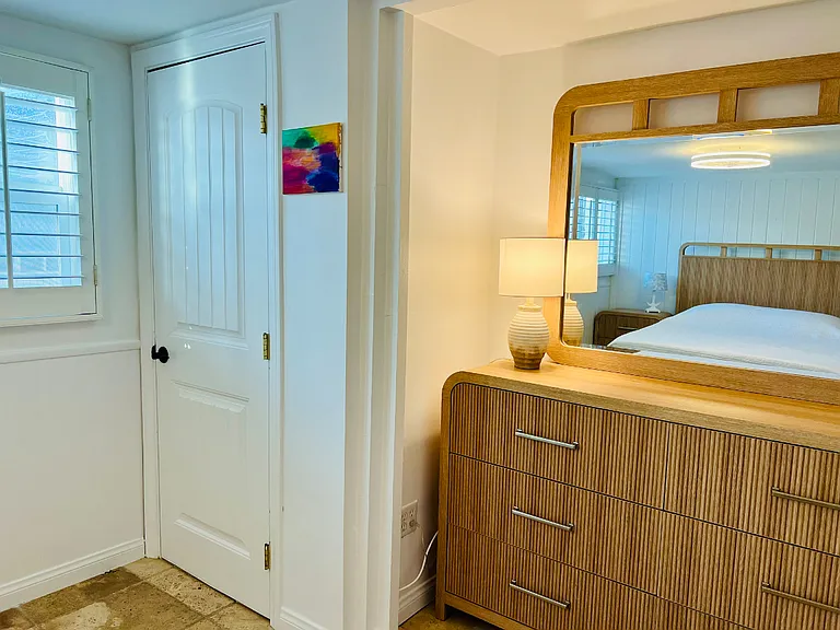 Guest bedroom with mirror on bureau, and the walk-in closet