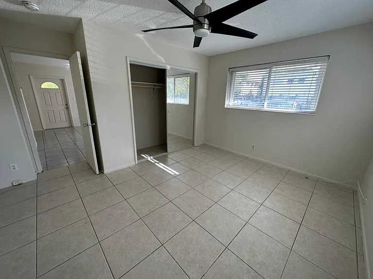 Large Bedroom from different angle ( rear exterior door) showing door to living room ( front door in the distance), mirrored 2nd closet and front east facing windows