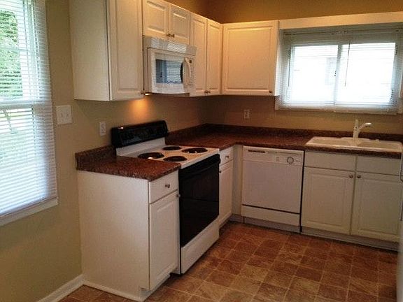 New White Kitchen Cabinets with Over the Range Microwave, Dishwasher, Electric Range and Refrigerator.
