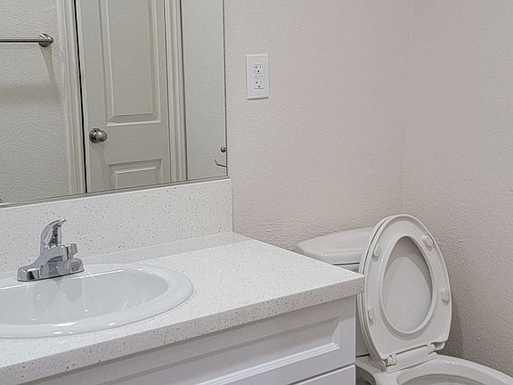 Bathroom with white vanity and toilet at Orlando Woods Apartments in El Cajon, California.