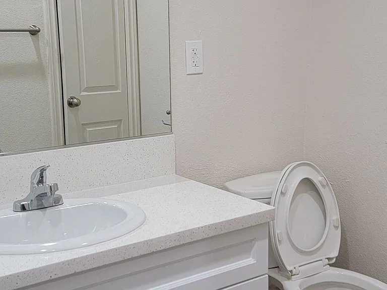 Bathroom with white vanity and toilet at Orlando Woods Apartments in El Cajon, California.