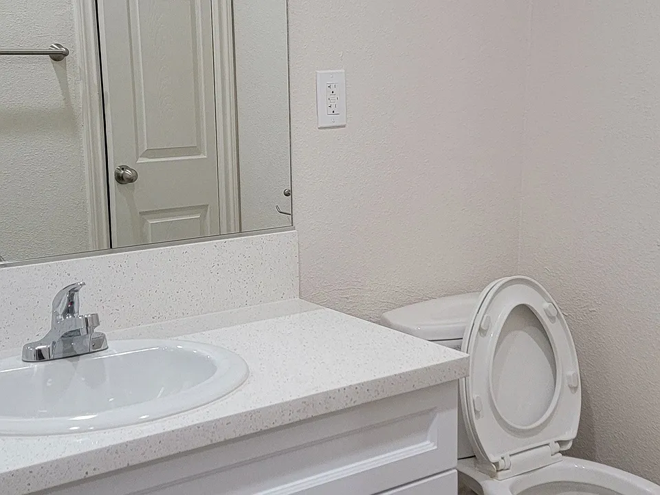 Bathroom with white vanity and toilet at Orlando Woods Apartments in El Cajon, California.