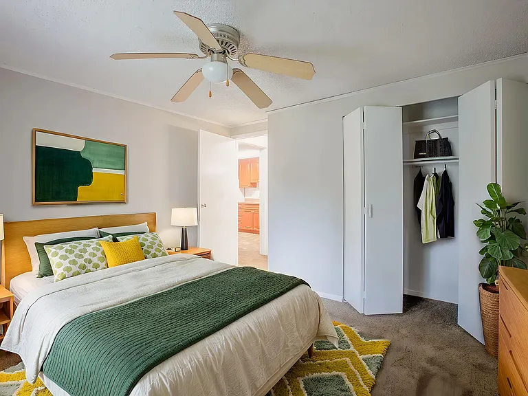 Inviting bedroom with modern decor, vibrant bedding, and ample closet space, perfect for relaxation.