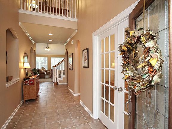Inviting 2-story foyer with decorative wall niche is flanked by the formal dining room and study. Half bath sits just beyond the study on the right.
