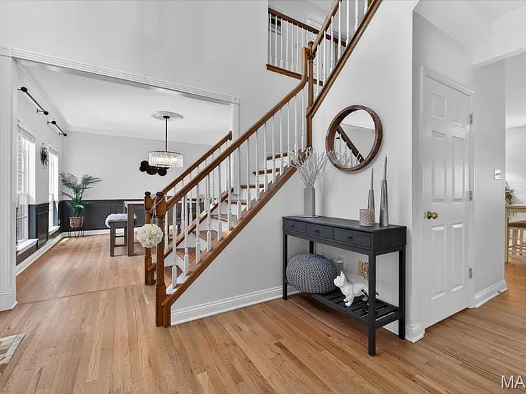 Hardwood flooring extending throughout the entryway and adjacent room