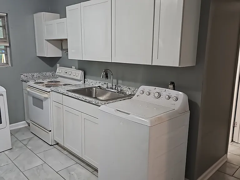 Freshly painted and tiled kitchen with washer, dryer, stove and refridgerator