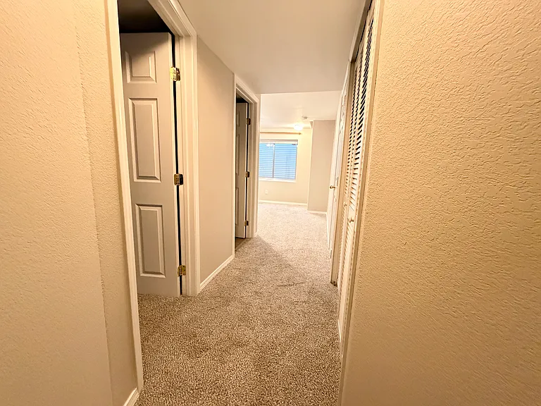 Basement hallway connecting the family room, third bedroom, updated full bathroom, and dedicated laundry area, providing a practical and functional lower-level layout.