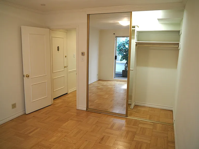 Bedroom and closet with glass sliding doors. Hallway to living room and kitchen to the left.