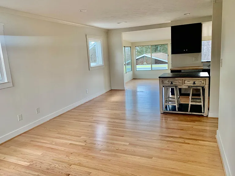 Living room with open floor plan to kitchen and window lined dining area