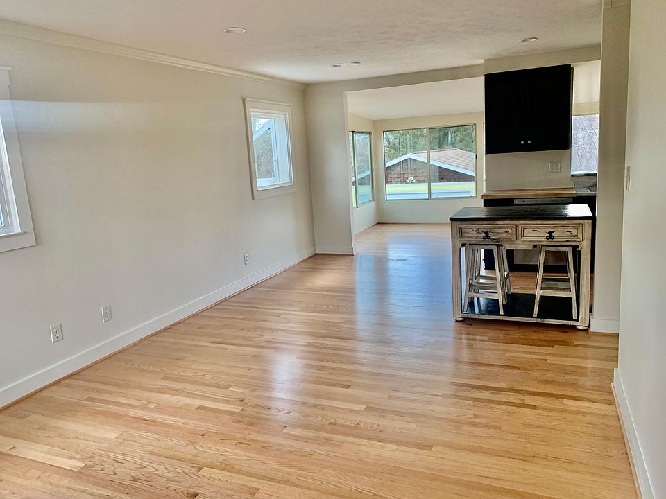 Living room with open floor plan to kitchen and window lined dining area