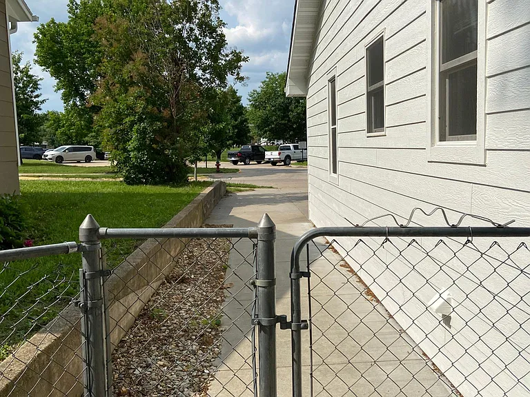 Chain-link gate on West side of house to backyard.
