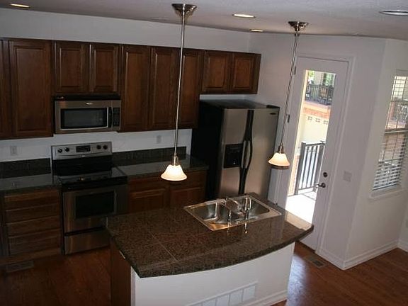 Kitchen with island, stainless steel appliances, pantry, and access to balcony.