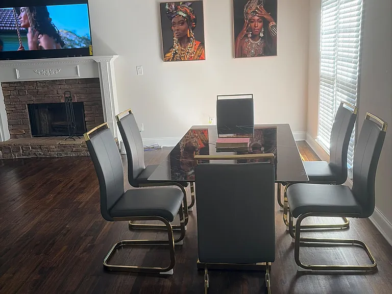 Dedicated dining area with a large table, hardwood flooring, and adjacent fireplace, plus plantation shutters for light contr