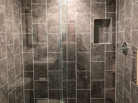 Brand new bathroom with floor to ceiling tile and sliding glass door