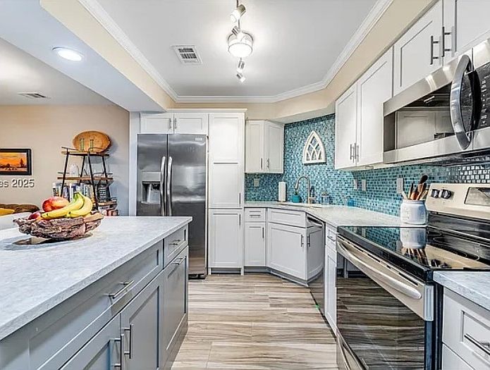 Gourmet kitchen with quartz countertops and island, stainless-steel appliances, and pantry.