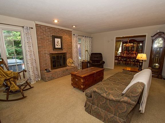 Living Room This spacious living room offers s cozy brick fireplace and a view of the woods behind the home.