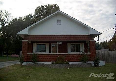 Front view of home - mostly all brick - covered front porch with swing.