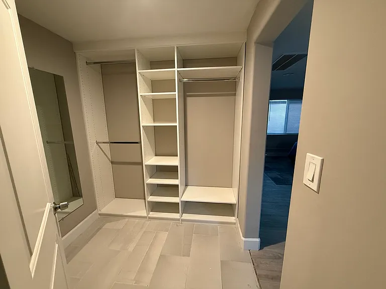 Custom Closet World storage system featuring built-in shelving, hanging space, and full-size mirror