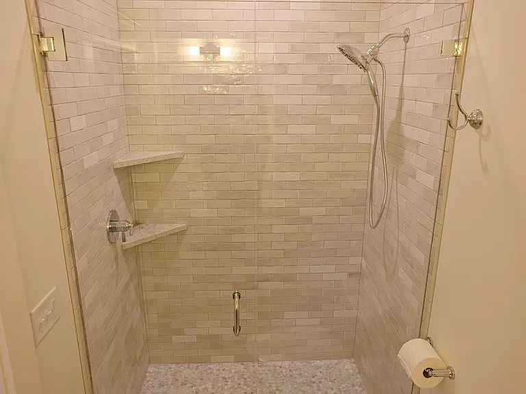 large tile shower with handheld shower wand.