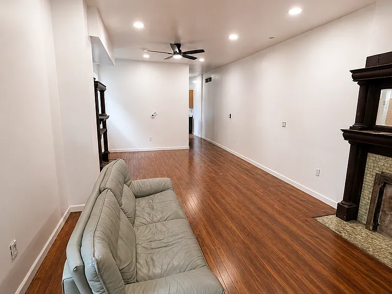 Spacious living room with antique fixtures and refurbished floors.