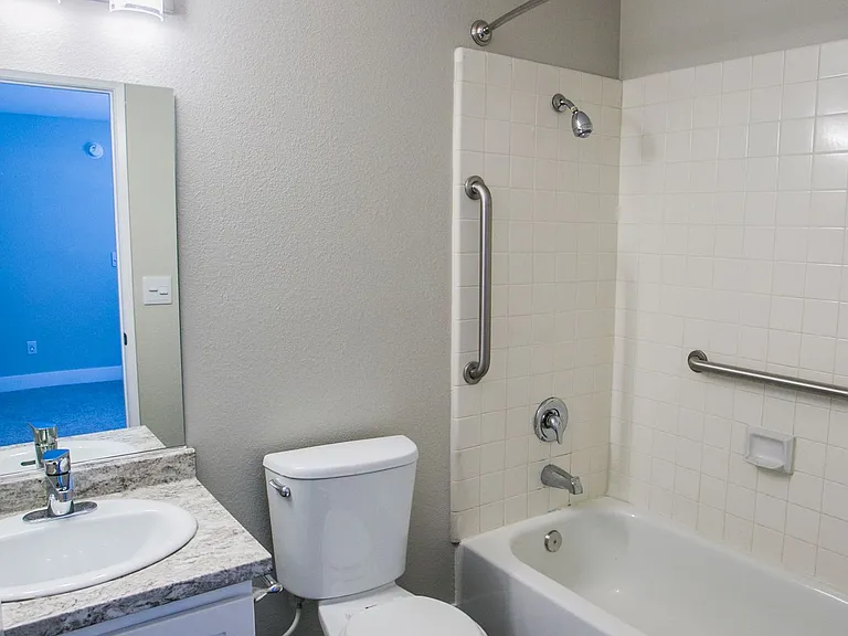 Bathroom with new lighting, wood-style flooring, and space-creating curved shower rod.