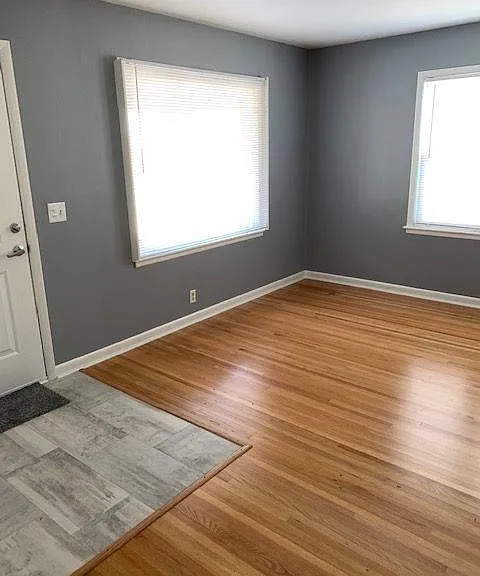 Living room with original beautiful oak hardwood floors, big picture window looking out to front porch/yard.
