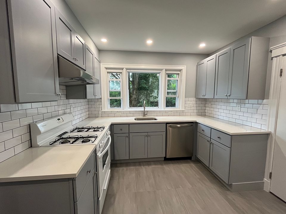 Newly renovated kitchen with new kitchen cabinets, quartz countertops, tile floors and backsplash, new electrical work and plumbing, and recessed lighting